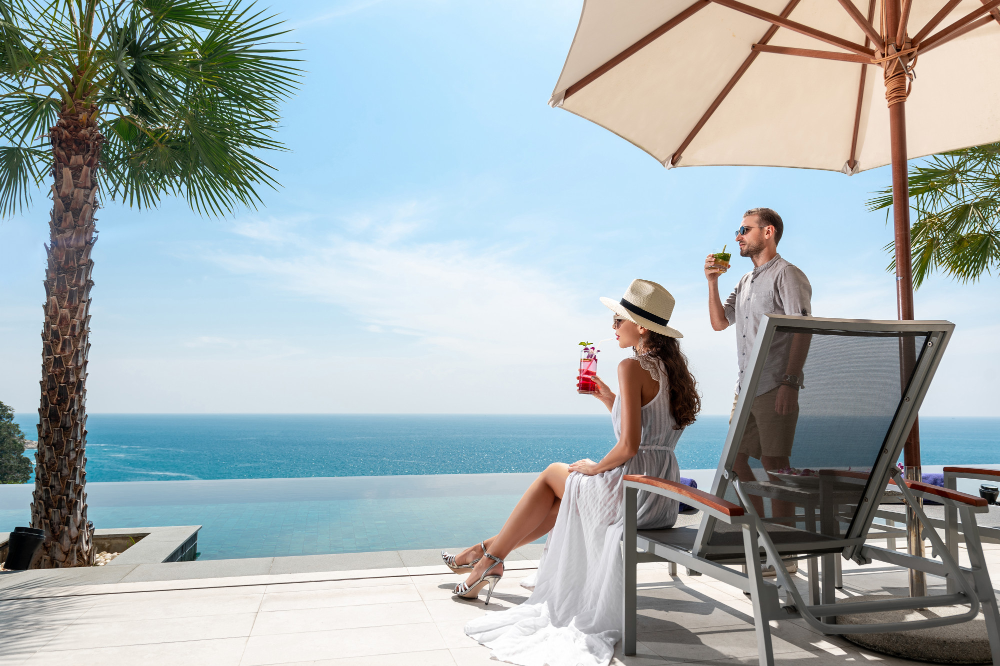 young-couple-have-rest-near-outdoor-pool-with-cocktails-their-hands